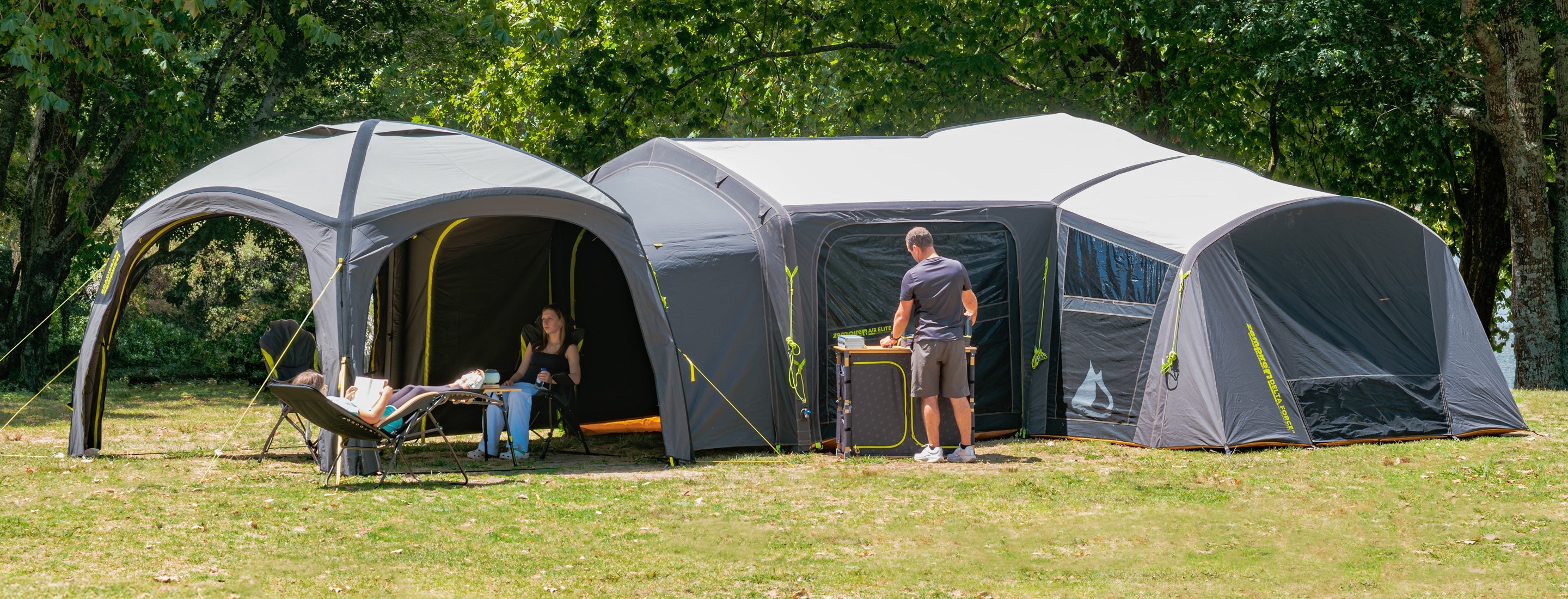 Llarge camping tent set up outdoors with people inside and around them.
